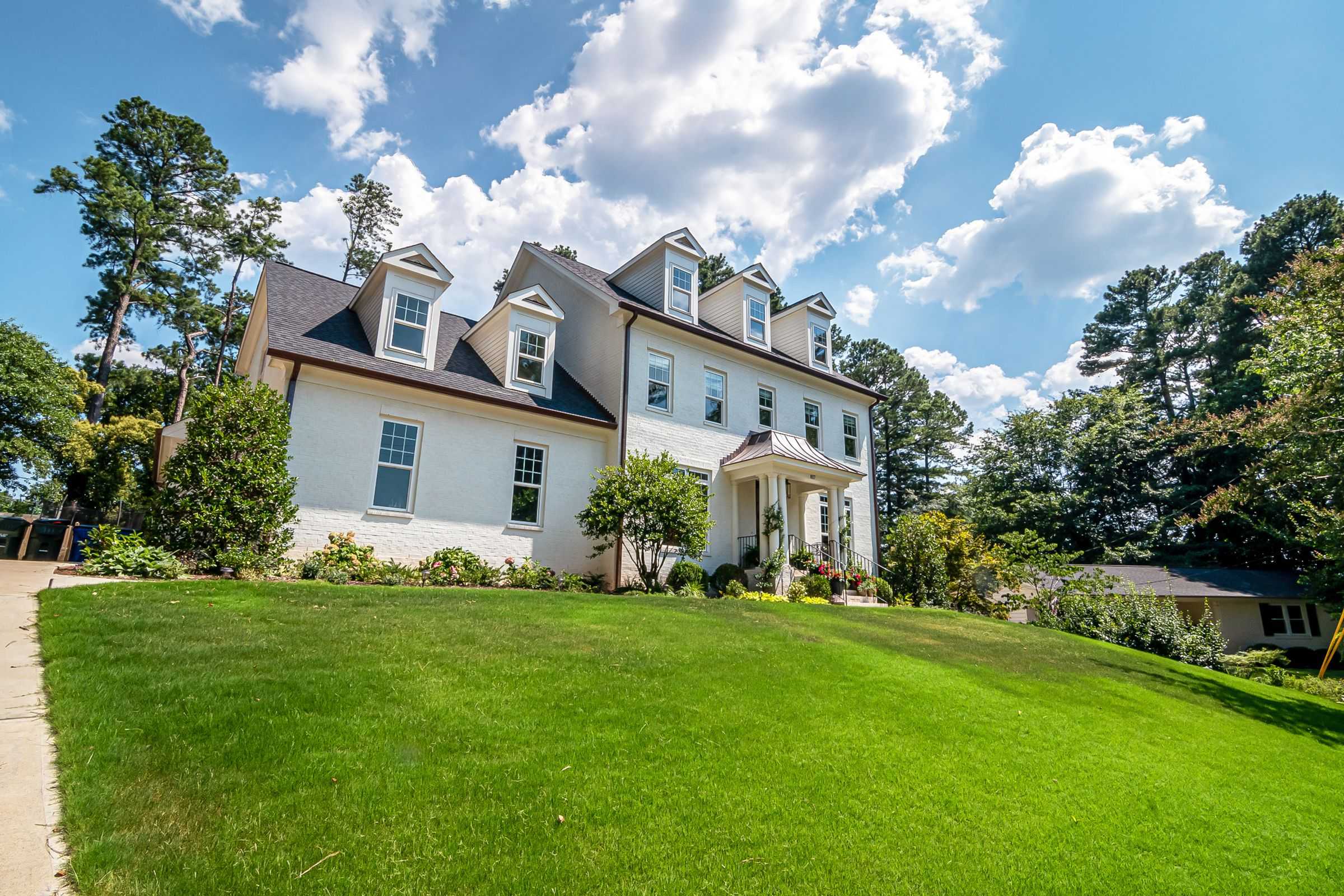 A white house on a green front lawn under a blue summer sky